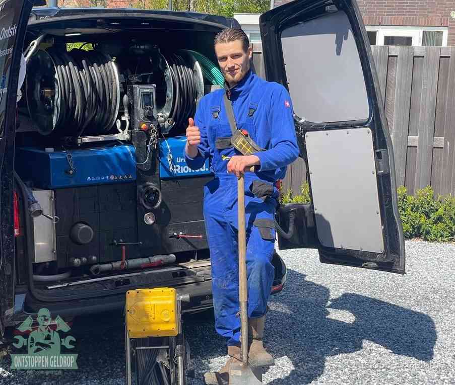 Een tevreden monteur met opgestoken duim naast de bestelbus, slim ingrijpen bespaart kosten bij een verstopte afvoer in Geldrop