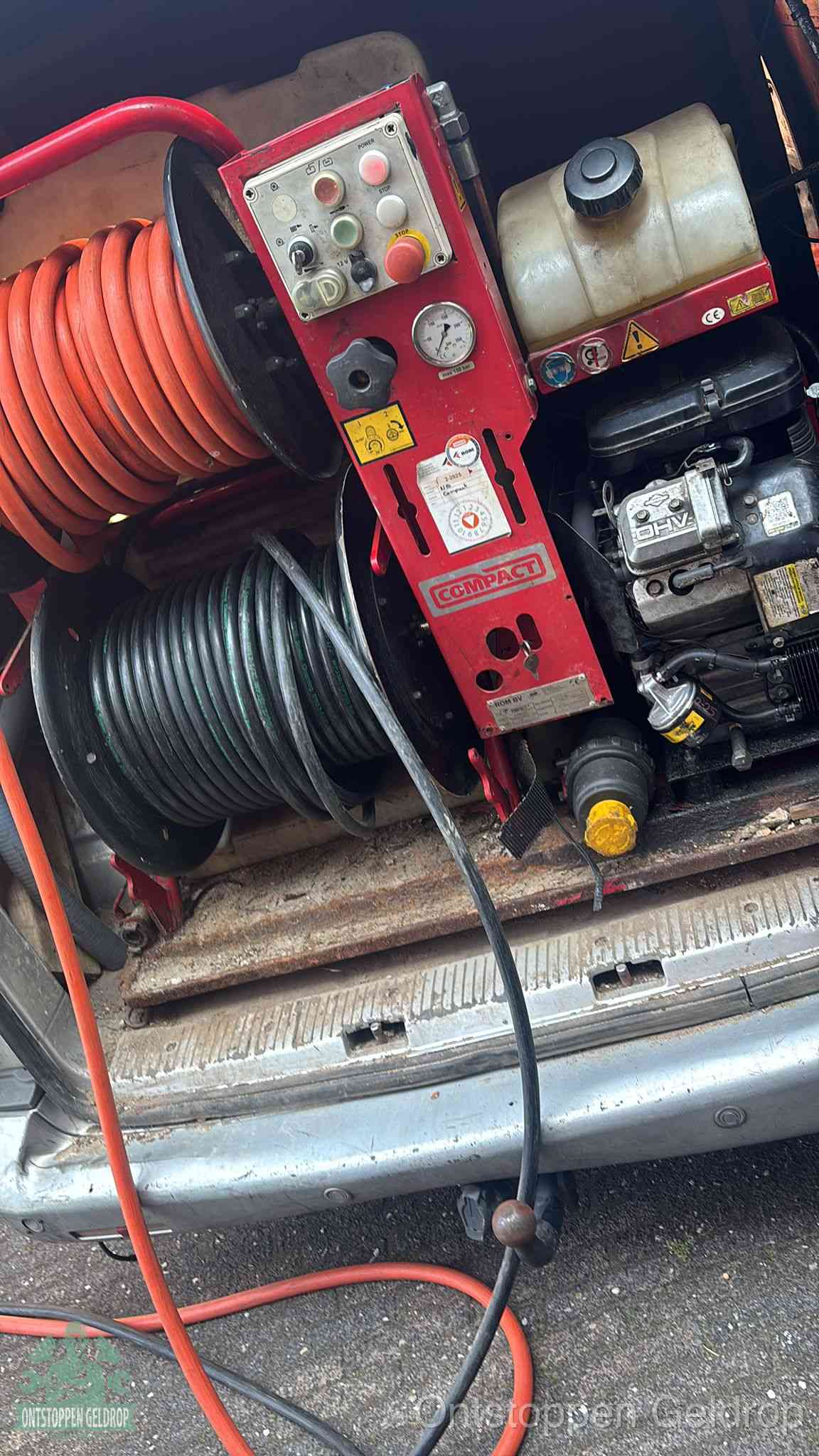 Een rood hogedruk-rioolreinigingstoestel in de laadbak van de bedrijfsbus, apparatuur voor een hardnekkige afvoerverstopping in Geldrop