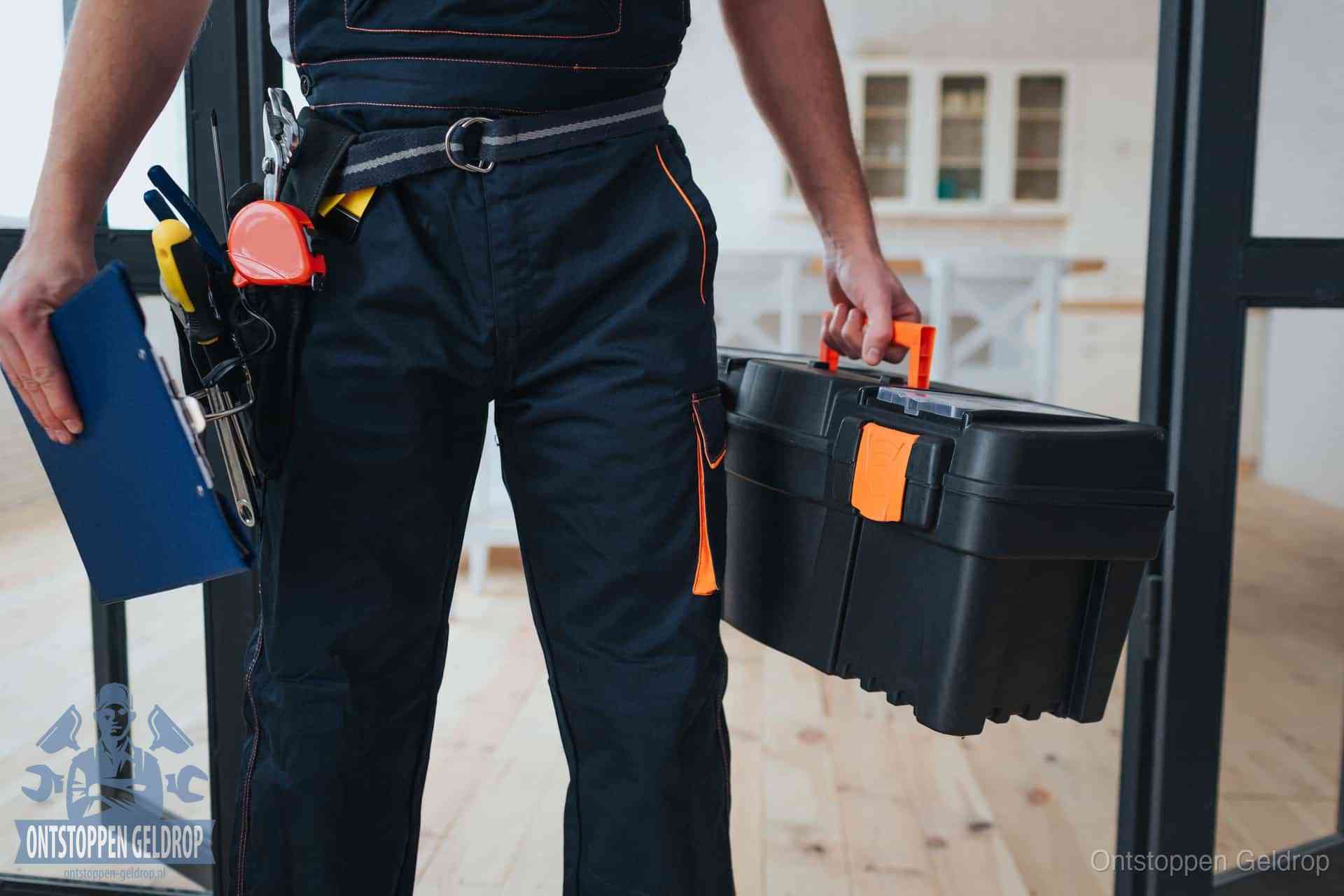 Een monteur met gereedschapsriem en klembord in een keuken, klaar om een transparante prijs voor het gootsteen ontstoppen in Geldrop te geven