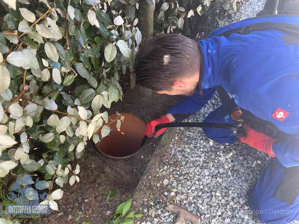 Monteur reinigt een rioolput met een slang, periodieke rioolreiniging in Geldrop