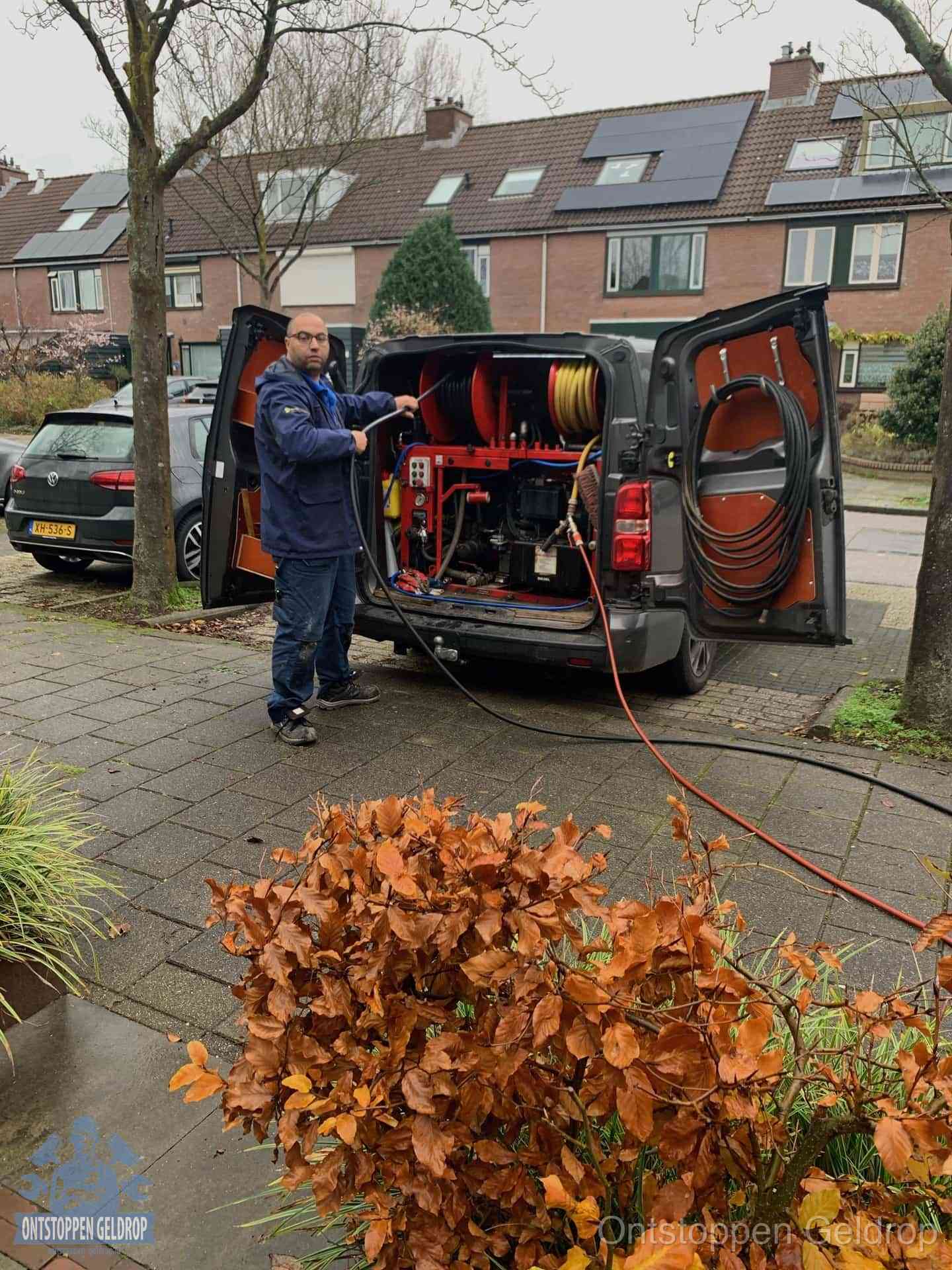 Monteur met rioolreinigingsbus levert rioolservice in de wijk in Geldrop