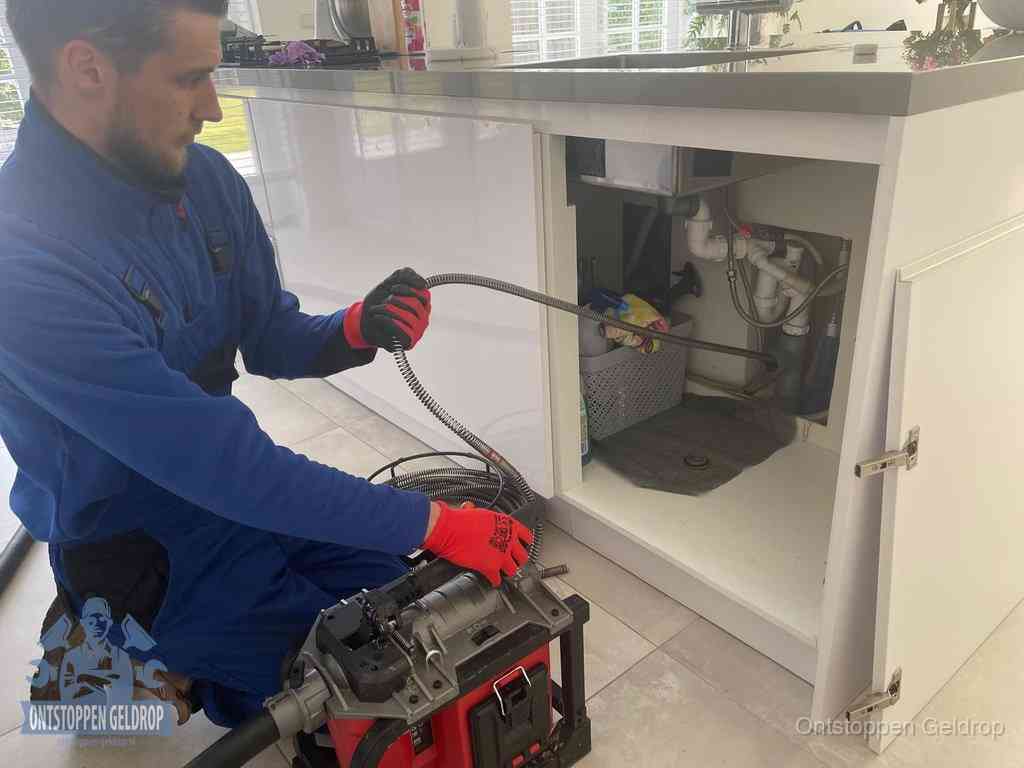 Een monteur reinigt de keukenafvoer grondig met een veermachine om terugkerende gootsteenverstoppingen te voorkomen in Geldrop
