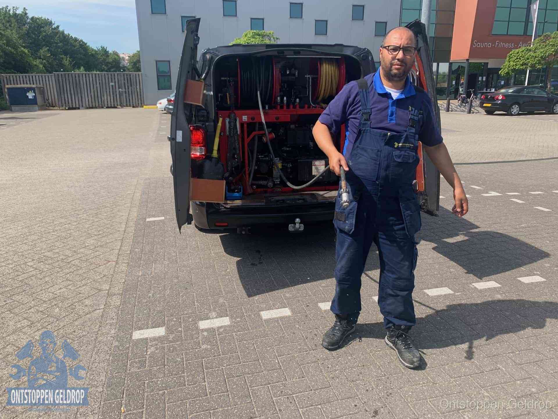 Een monteur bij zijn bestelbus met een hogedruk- en rioolreinigingsunit, klaar om de oorzaak van terugkerende wc-verstoppingen aan te pakken in Geldrop Een monteur bij zijn bestelbus met een hogedruk- en rioolreinigingsunit, klaar om de oorzaak van terugkerende wc-verstoppingen aan te pakken in Geldrop