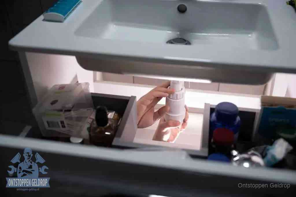 Een pompfles met zeep boven een wastafel in de toiletruimte, de warm water en afwasmiddel-methode om de wc te ontstoppen in Geldrop Een pompfles met zeep boven een wastafel in de toiletruimte, de warm water en afwasmiddel-methode om de wc te ontstoppen in Geldrop