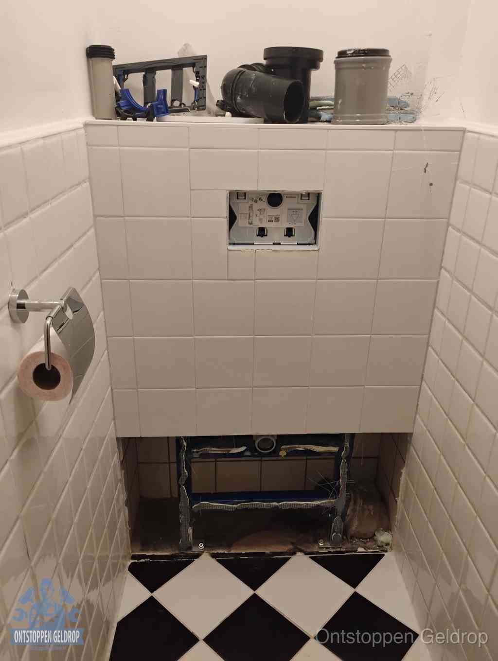 Een toiletruimte waar het hangtoilet en de inbouwreservoir-onderdelen zijn vrijgelegd voor onderhoud, periodiek nazicht voorkomt een wc-verstopping in Geldrop Een toiletruimte waar het hangtoilet en de inbouwreservoir-onderdelen zijn vrijgelegd voor onderhoud, periodiek nazicht voorkomt een wc-verstopping in Geldrop